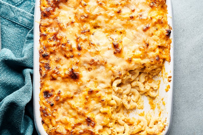A white baking dish filled with baked macaroni and a golden cheese topping