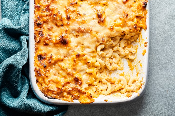 A white baking dish filled with baked macaroni and a golden cheese topping