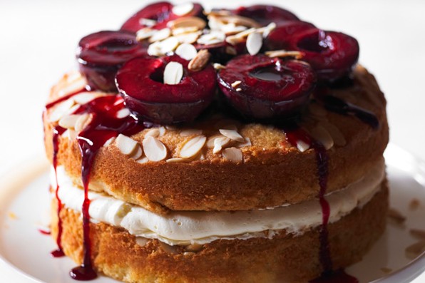 Layer cake topped with plums, on stand