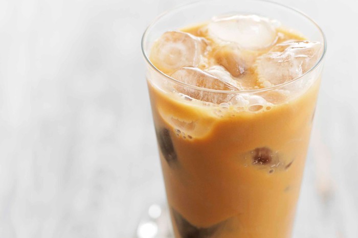 A tall glass filled with iced latte and ice