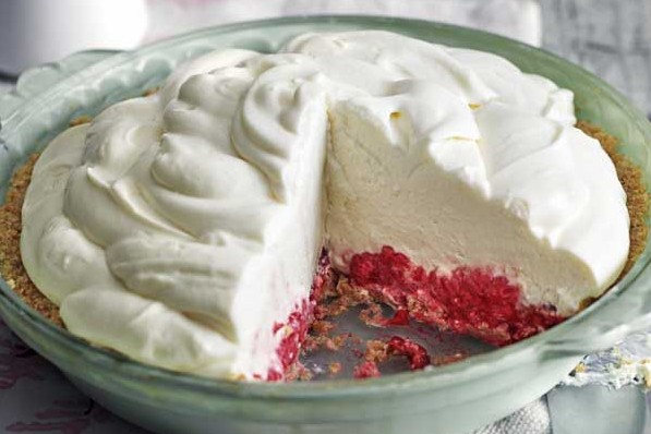 Cross-section of marshmallow cheesecake with raspberry base, on a plate