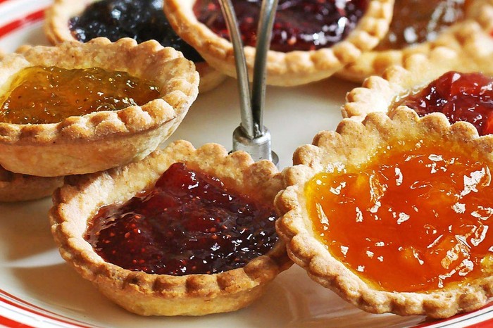 Mini jam tarts on a serving plate, with multicoloured jam fillings
