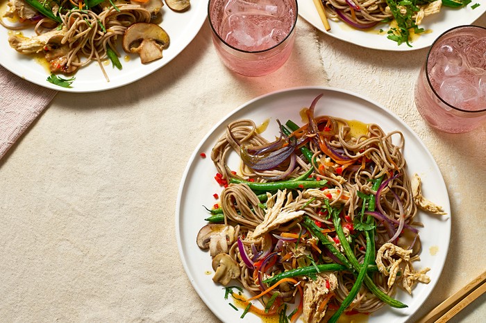 Three plates of colourful stir-fry with drinks on the side