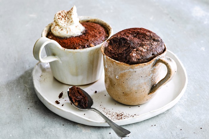 two rustic, handmade mugs on a side plate filled with chocolate sponge