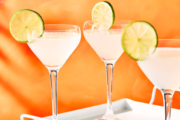 Daiquiri cocktails in glasses on tray with lime wheels