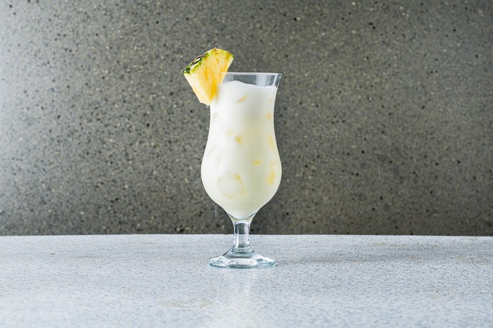 Piña colada cocktail in a glass, with pineapple wedge garnish