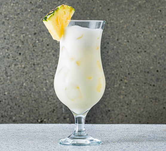 Piña colada cocktail in a glass, with pineapple wedge garnish