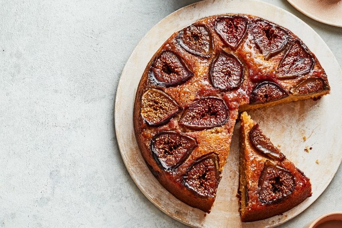 A cake topped with baked sliced figs on a beige stone plate