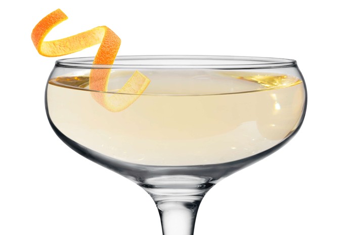 A cocktail glass with a twist of lemon on top