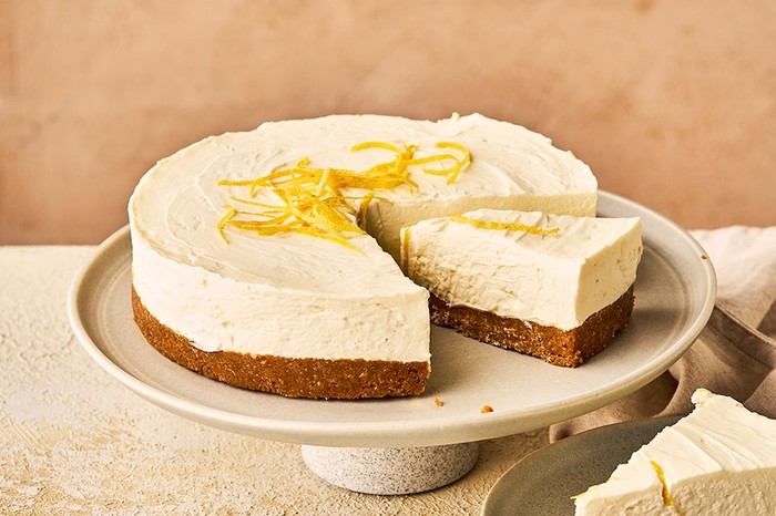 Cheesecake on a stand and plate with lemon zest on top