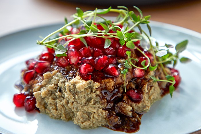 Baba ghanoush on a blue plate topped with pomegranate seeds