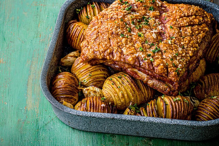 Roast pork with hasselback potatoes in a roasting tin