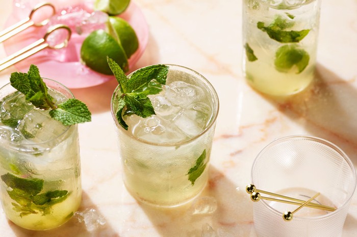 Three glasses of mojito, filled with ice, limes and garnished with mint leaves