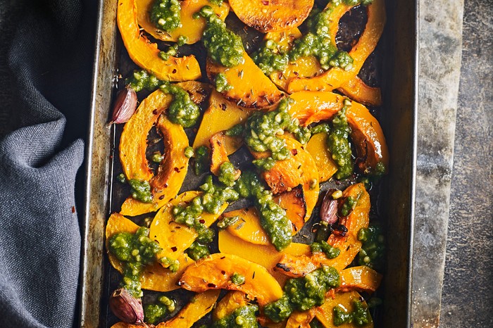Roasted butternut squash wedges with pesto on a baking tray