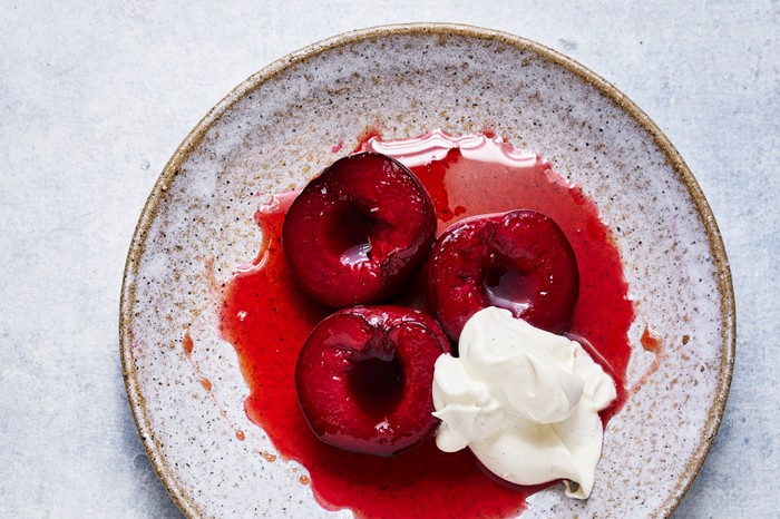 Roasted Plums served with cream on a speckled grey plate