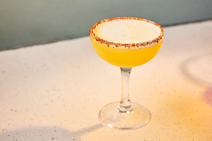 A Pineapple and shichimi margarita with a red flaked rim in a coupe glass