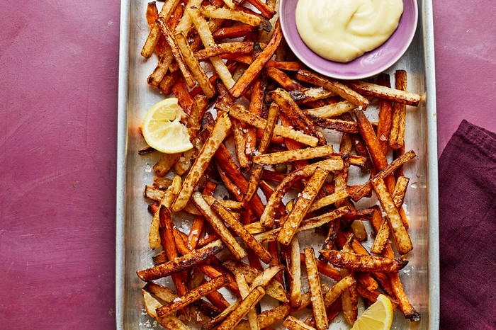Baking tray of sweet potato and kohlrabi fries with a ramekin of wasabi mayonnaise.